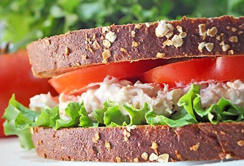 Photo of a tuna sandwich with lettuce and tomatoes.