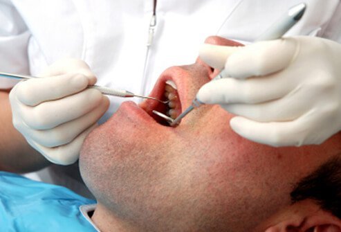 A dentist examines a patient's mouth.