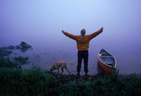 Woman and dog by lake.