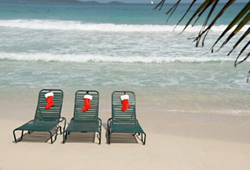 Three lounge chairs on the beach with Christmas stockings.