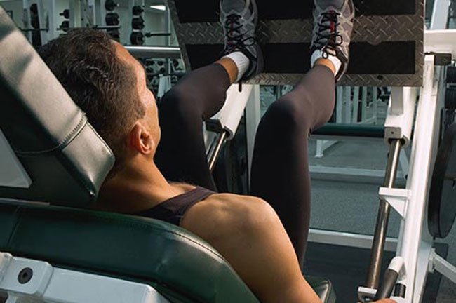 Sit on a leg-press machine with your back and head against the support and your feet flat on the foot plate.