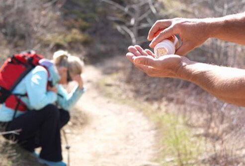 A hiker gives a fellow hiker, that's not feeling well, pain reliever medicine.
