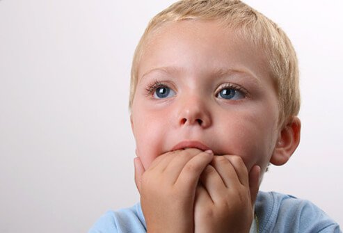 A boy fidgets with his hands in his mouth.