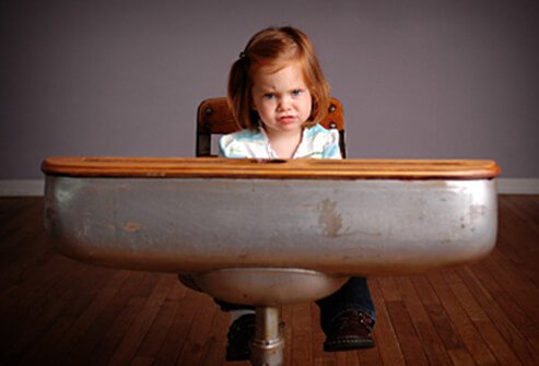 A girl is not happy about having to stay in her seat during class.