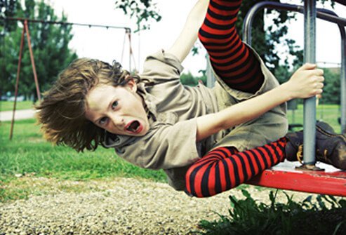 A girl yells while climbing on playground equipment.