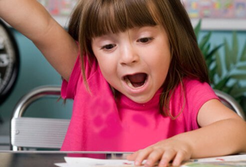 A girl raises her hand and yells out an answer in class.