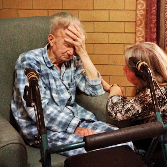 An elderly man in his pajamas with a caregiver.