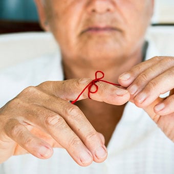 A close up of a red bow tied onto a man's finger.
