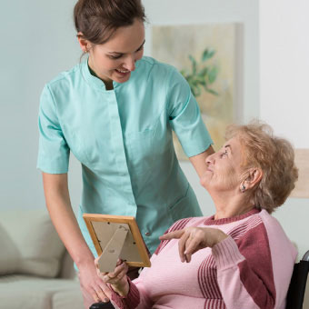 An elderly woman points at a picture frame.