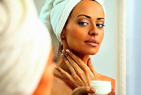 Photo of a woman checking her complexion in the mirror.