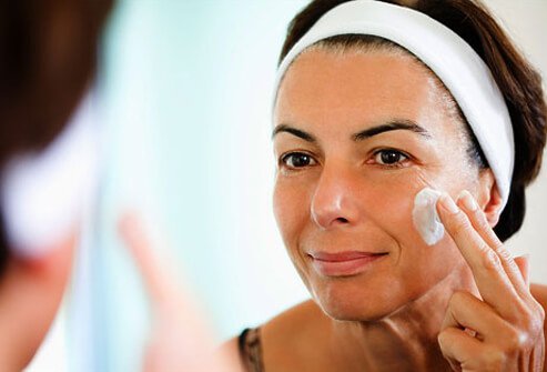 Photo of a woman moisturizing her face.