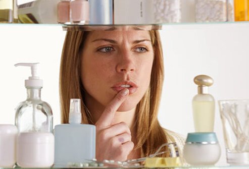 Photo of a woman choosing skin cream from a cabinet.