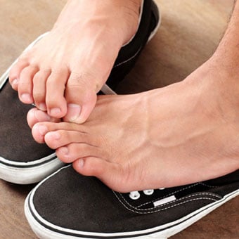 A boy scratches his itchy athlete's foot.