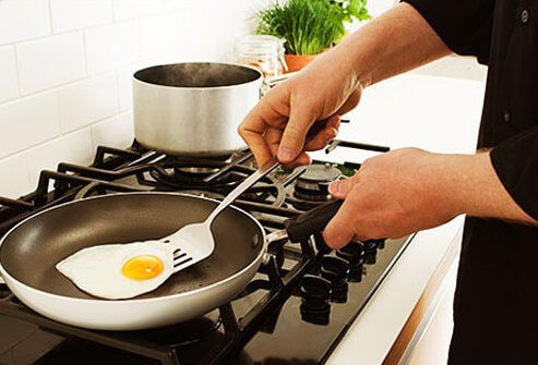 Photo of a person frying an egg sunny side up.