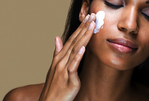 Photo of woman applying face cream.