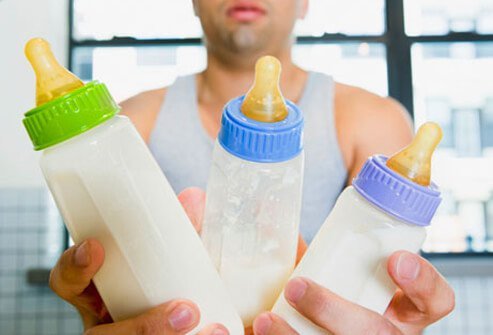 A father holding three baby bottles.