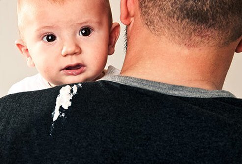 A baby spitting up on his dad's shirt.