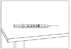 Carefully set the syringe with needle down on the table - Illustration