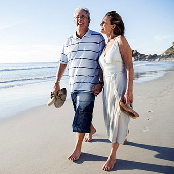 A senior couple walking on the beach.