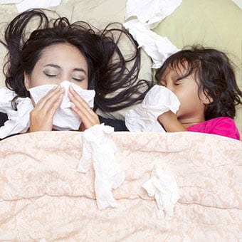 A mother and daughter both suffer from bronchitis in bed.
