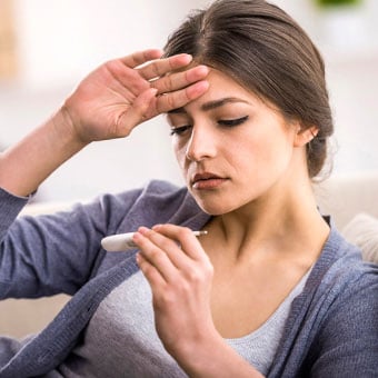 A woman with a fever takes her temperature.