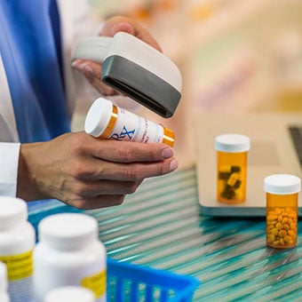 A pharmacist scans prescription medications.