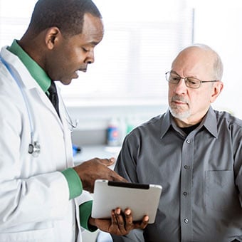 A doctor discusses constipation treatments with a male patient.