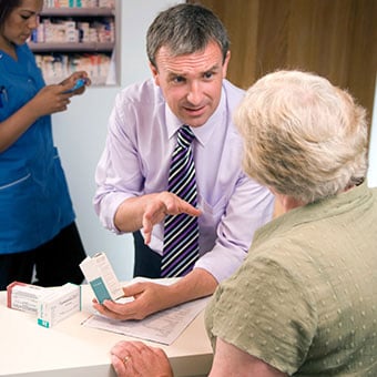 A pharmacist explains medication side effects to a patient.