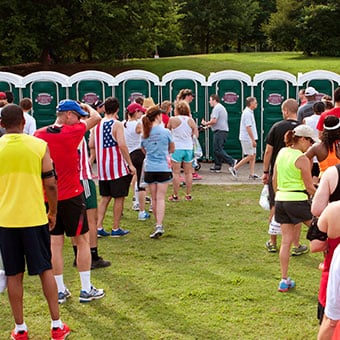 A line of runners waits in line to use portable toilets.