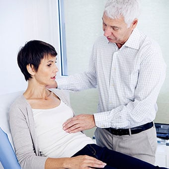 A doctor examines a female patient's abdomen.