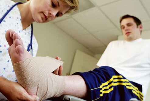 A nurse applies a compression bandage to a man's ankle to keep the swelling down.