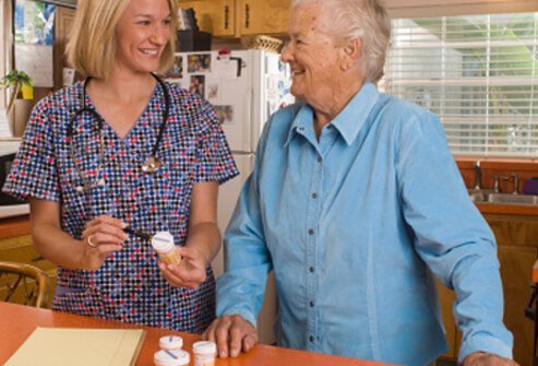 A caregiver helping an elderly dementia patient with her medications.