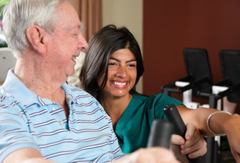 A senior man with dementia exercising with the supervision of his caregiver.