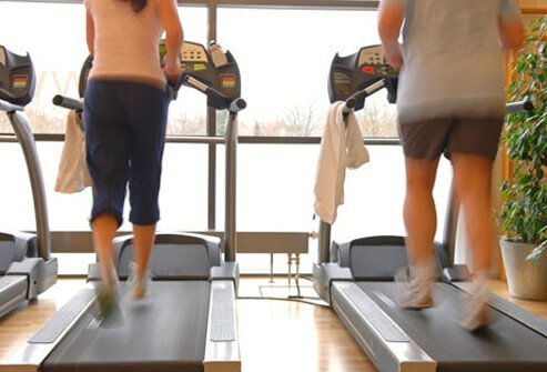 A couple jogging on the treadmill.