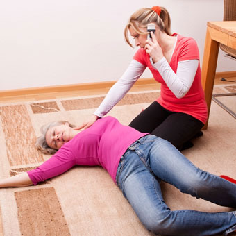 A woman calls 9-1-1 to help a woman who has fainted.