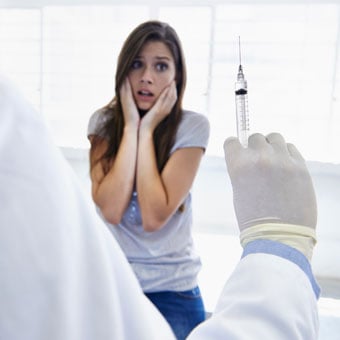 A woman recoils at the sight of a needle.