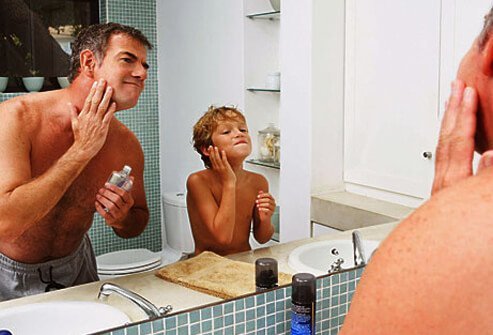 Photo of father and son applying aftershave.