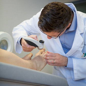A doctor examines a patient's toenails.