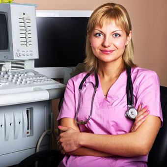 A female doctor sits next to an ultrasound machine.