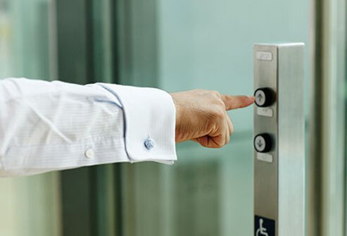 A man pushes the elevator buttons.