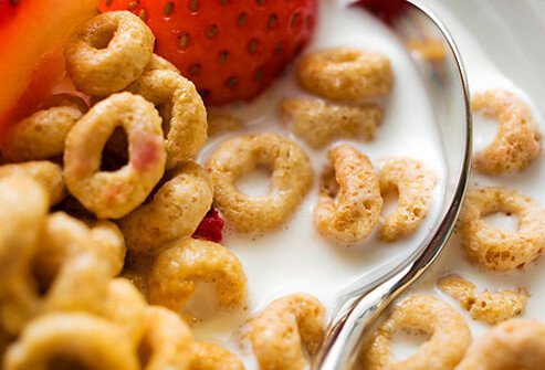 Bowl of cereal, milk, and strawberries.