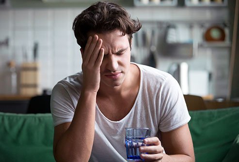 Man sitting at his desk holding the side of his head.
