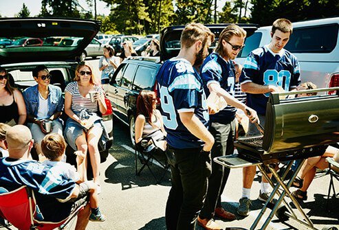 A group of tailgaters serve up hot dogs.