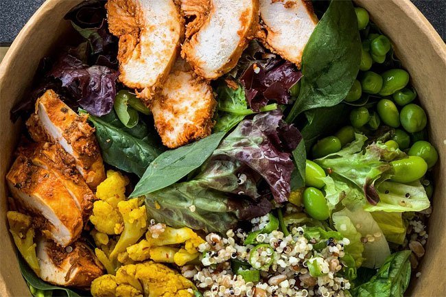 Build a salad bowl with rotisserie chicken, greens, vegetables, quinoa, avocado, nuts and cheese topped with an oil-based dressing.