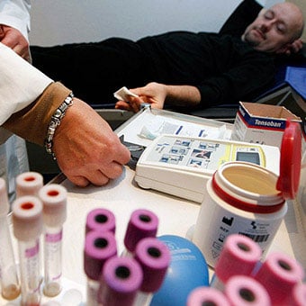 A nurse puts a blood sample into an automated machine for hematocrit measurements.