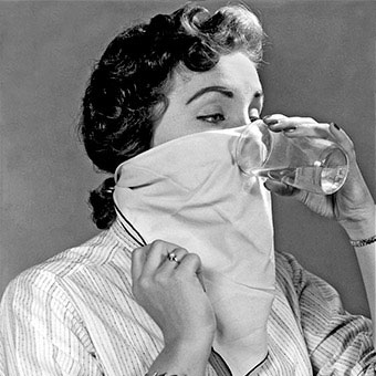 An woman drinks water through a napkin, an old wives tale hiccup remedy.