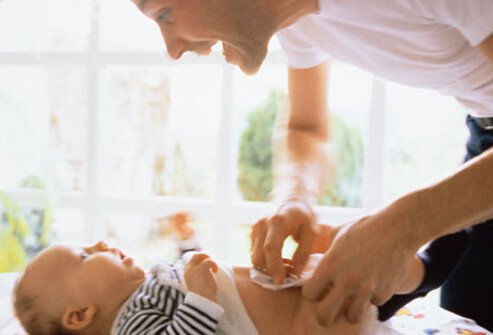 Photo of a dad changing his baby's diaper.