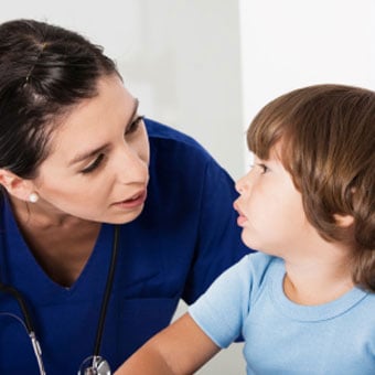 A doctor checks a boy's face for impetigo.