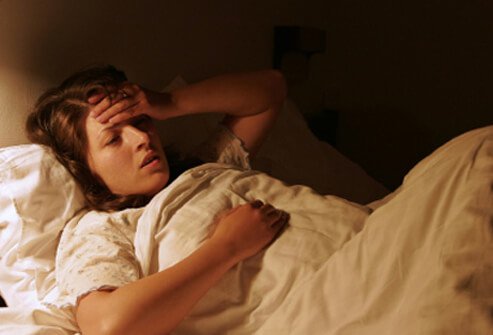 A girl suffering from mono lies in bed.