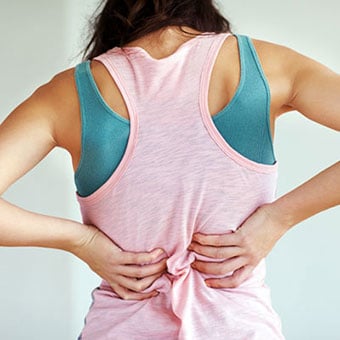 A woman experiences a muscle spasm in her back.